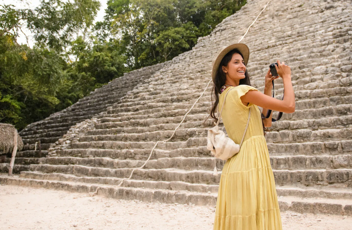 a young woman smiles and takes a picture of Mexican ruins while on vacation with travel insurance for Mexico