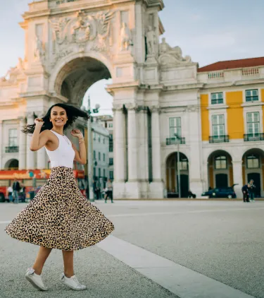 a young woman spins in Commerce Square, Lisbon, insured with travel insurance for Portugal