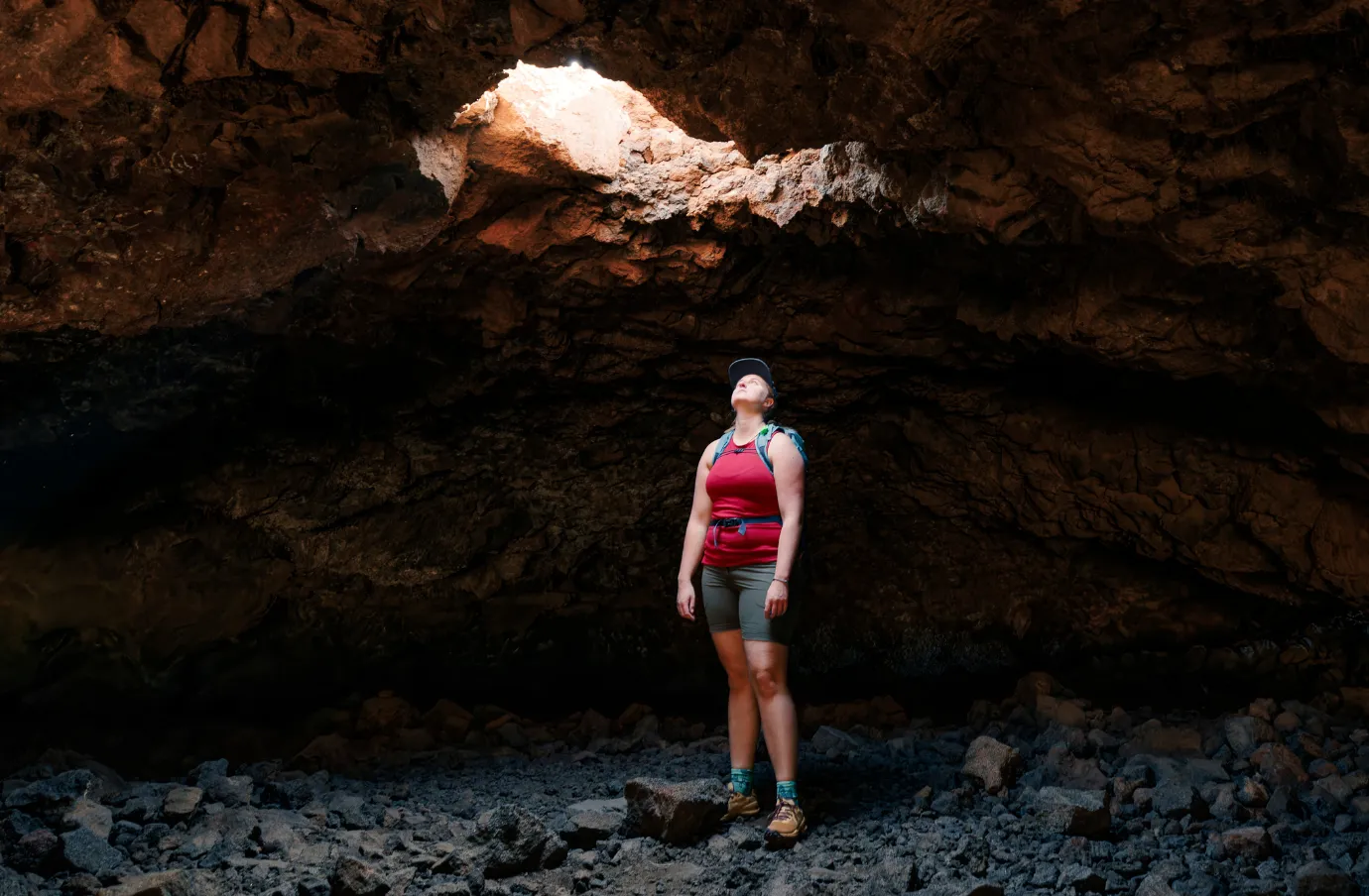 a woman hikes through a lava tube on vacation, insured with travel insurance for Hawaii