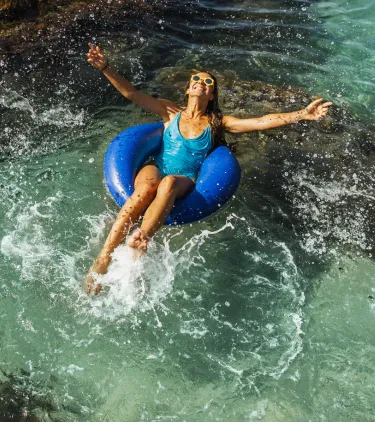 Woman with travel insurance for her all-inclusive vacation floating on an inner tube in the ocean