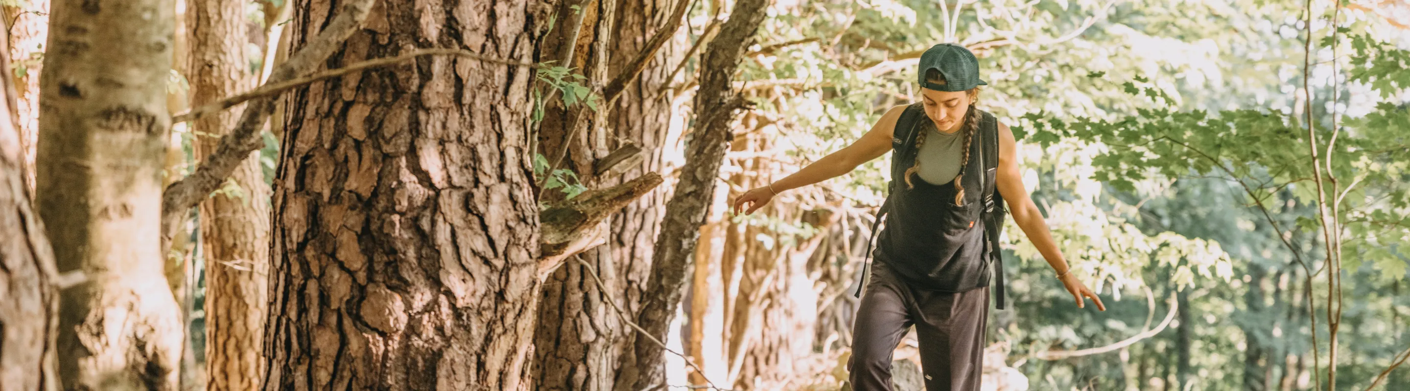 a young woman hikes a wooded trail in upstate New York, insured with travel insurance for New York 