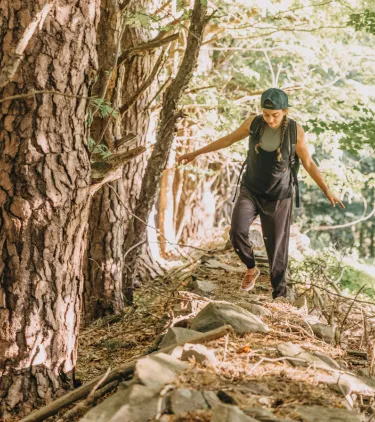a young woman hikes a wooded trail in upstate New York, insured with travel insurance for New York 