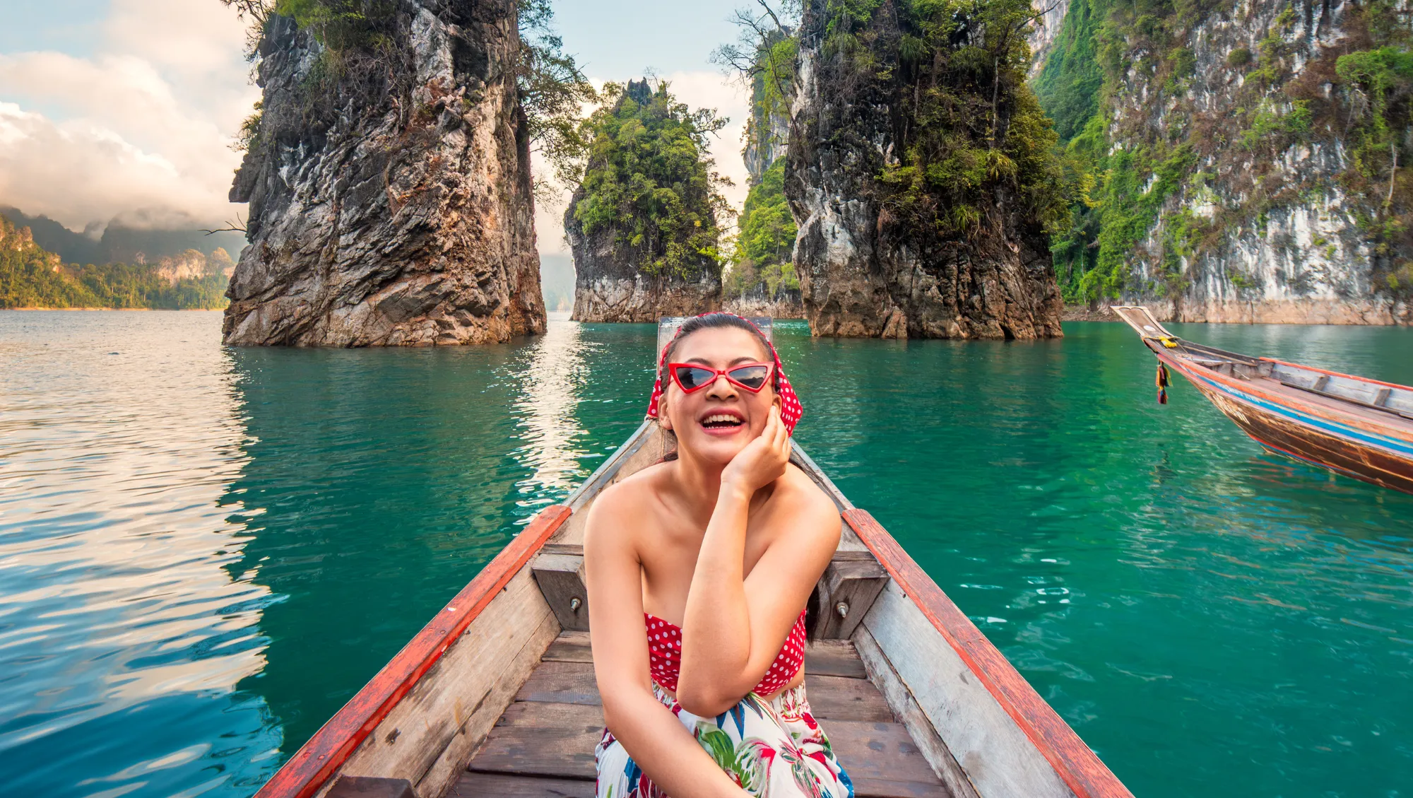 a young woman sits on a longtail boat among limestone cliffs on vacation after reading our LGBTQ travel tips