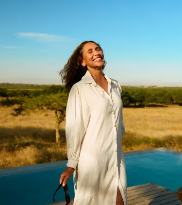 a woman stands in front of an infinity pool at a luxury safari lodge, insured with travel insurance for Africa 