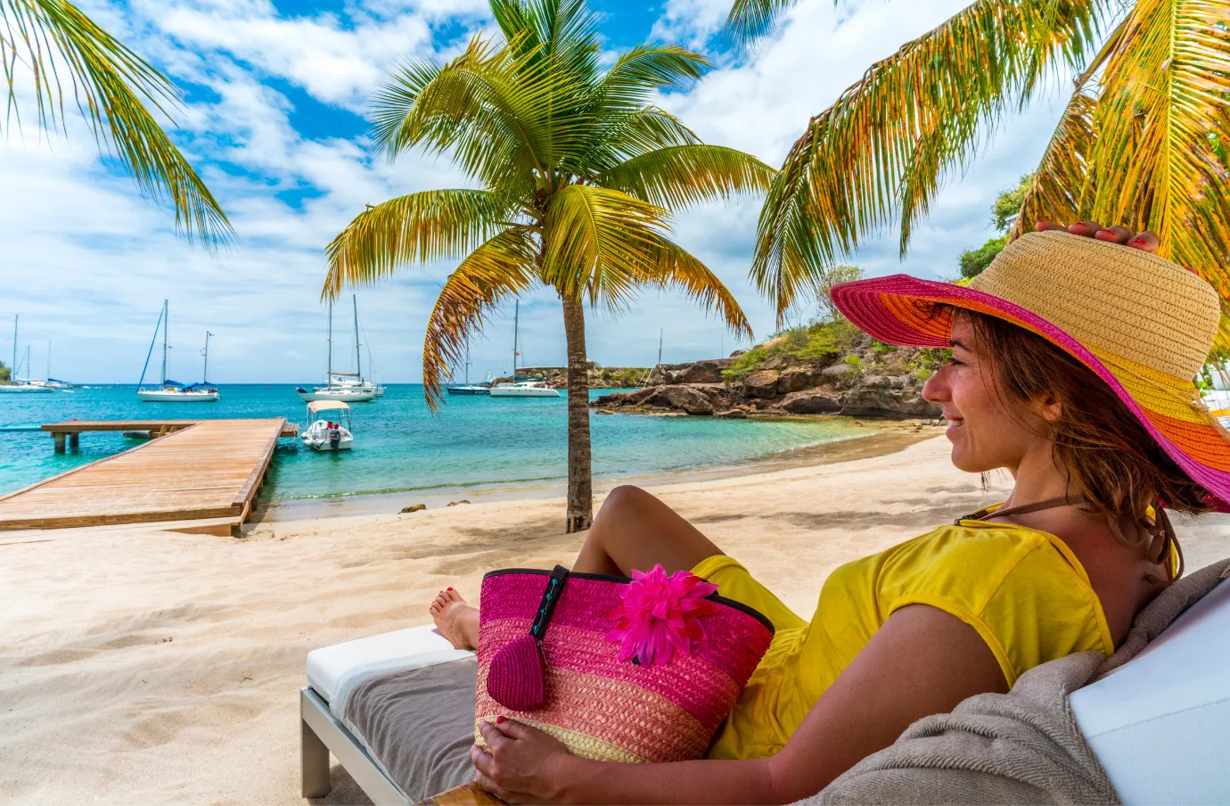 a woman with travel insurance for the Dominican Republic relaxes on a beach lounger near palm trees and turquoise water 