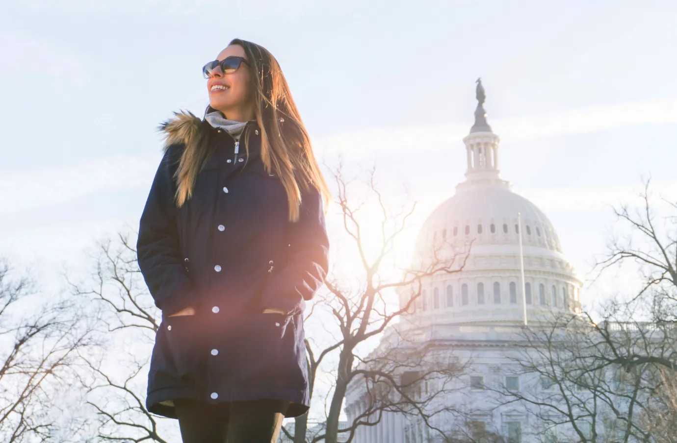 a woman with travel insurance for Washington, D.C. stands in front of the U.S. Capitol dome
