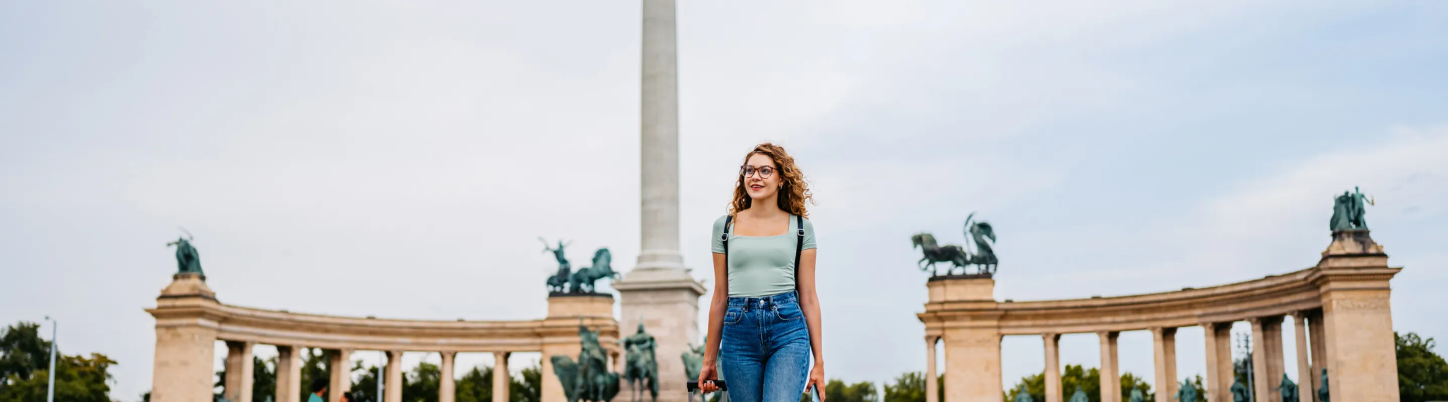 woman with baggage insurance, dragging her suitcase in Heroes' Square, Budapest 