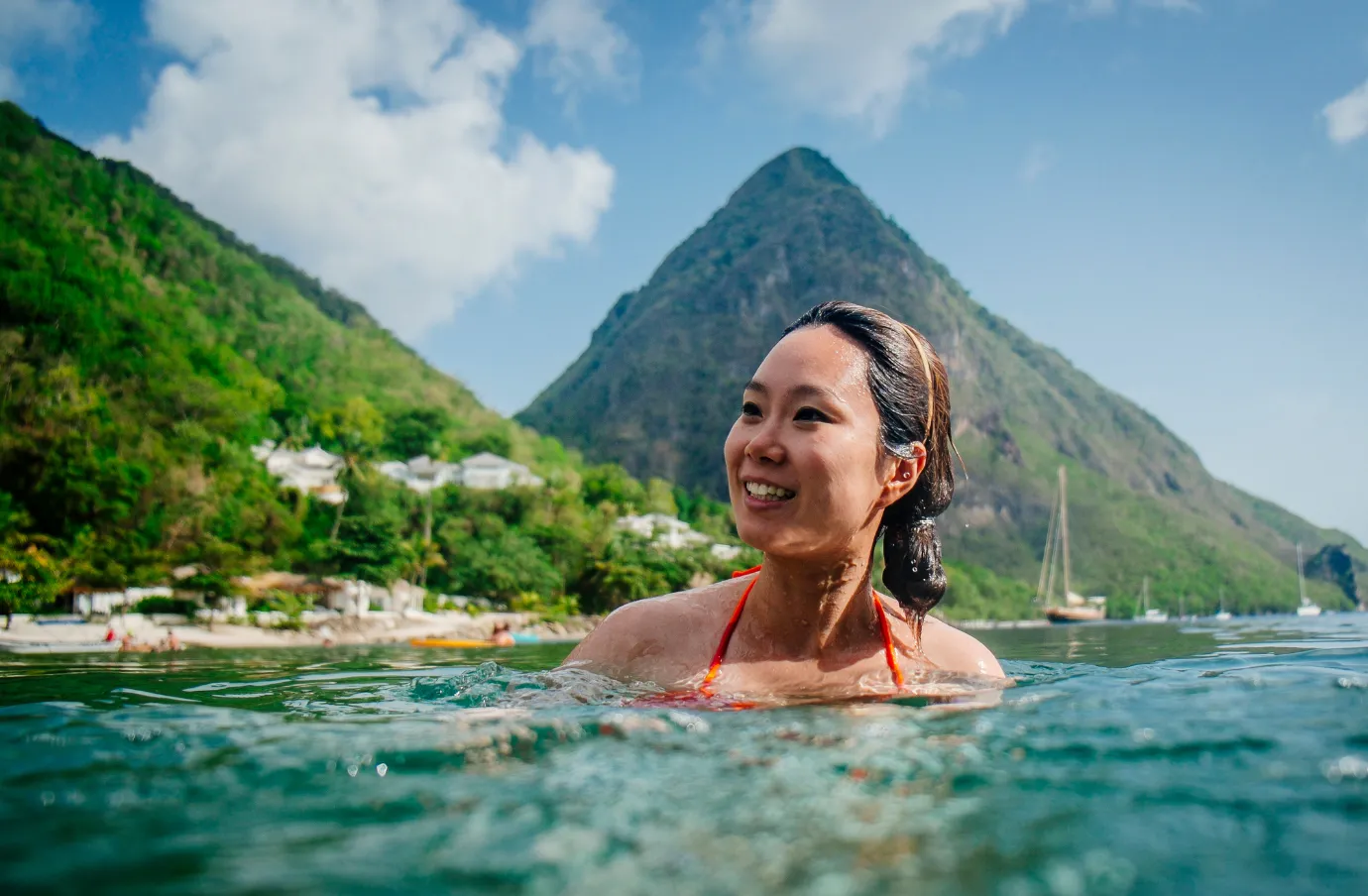 a woman with travel insurance for the Caribbean enjoys a swim in calm tropical waters near an island shoreline