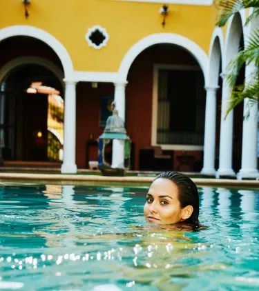 a woman with travel insurance for Mexico swims in her hotel's pool