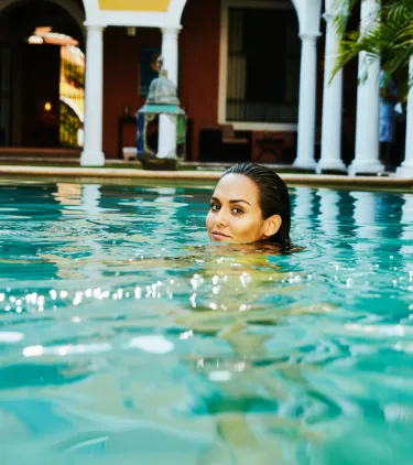 a woman with travel insurance for Mexico swims in her hotel's pool