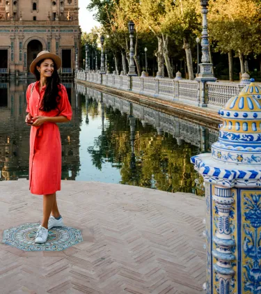 a young woman in a dress visits Plaza de Espana, Seville, insured with travel insurance for Spain