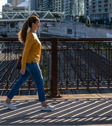 a woman in a yellow shirt walks through downtown Toronto, insured with travel insurance for Canada 