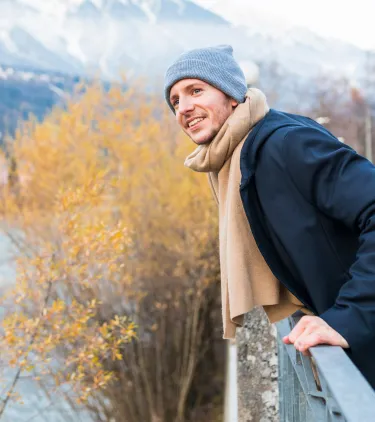 a young man with travel insurance for Austria overlooks the scenic town of Innsbruck in winter clothes 