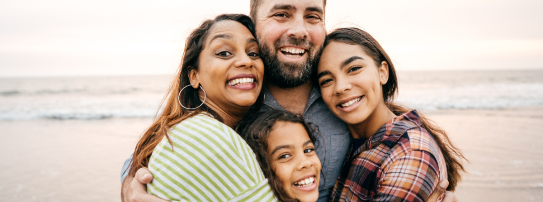 Smiling parents with two children, as they use a United States travel guide to explore top beaches in the USA