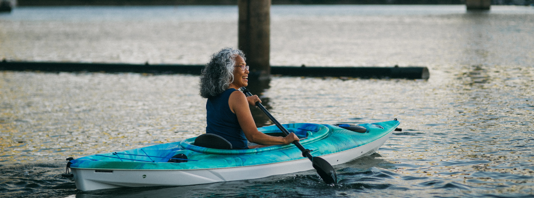 Senior woman smiling and kayaking in Portland, Oregan, one of the best places to travel as a solo female in the U.S.