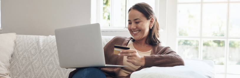 Woman holding a credit card and looking at her laptop to see how much travel insurance is for her trip