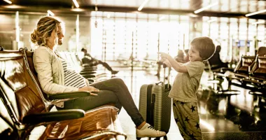 Mother at the airport for travel during pregnancy with her young son.