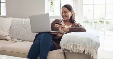 Woman holding a credit card and looking at her laptop to see how much travel insurance is for her trip