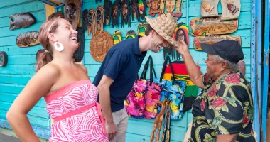 Couple trying on hats at a market during Caribbean travel season