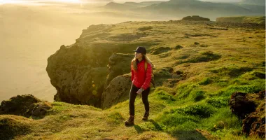 Woman hiking on a cliff in Iceland, one of the best solo travel destinations
