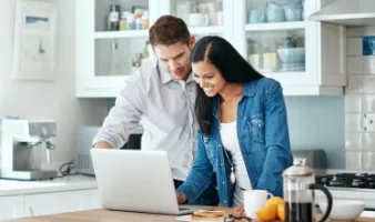 Smiling couple trying to calculate trip cost for their travel insurance policy.