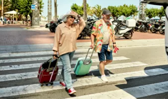 Senior couple crossing the street with suitcases that could be stolen on vacation.