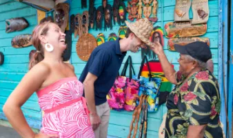Couple trying on hats at a market during Caribbean travel season