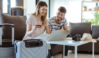 Young couple with laptop and suitcases choosing between credit card travel insurane and a policy.