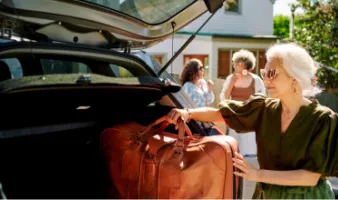Elderly woman loading her baggage into a car trunk, which later becomes lost luggage