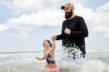 father holding daughter's hand and walking through waves in the Florida ocean during hurricane season