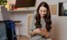 Smiling woman using mobile phone while packing
